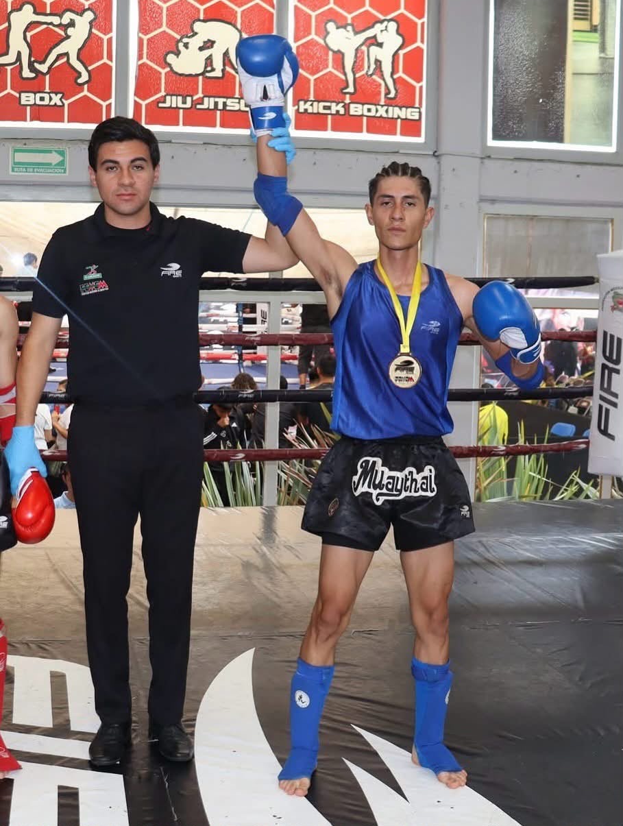 Peleador de DFC con medalla y mano levantada por el árbitro